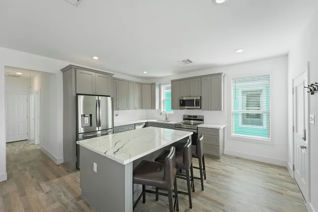 a kitchen with stainless steel appliances a dining table chairs and a refrigerator