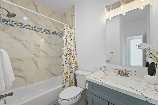 a bathroom with a granite countertop sink a toilet a mirror and shower