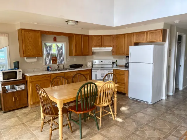 a kitchen with stainless steel appliances a refrigerator a stove a sink dishwasher and a dining table with wooden cabinet