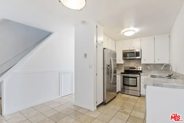 a kitchen with granite countertop white cabinets and white appliances