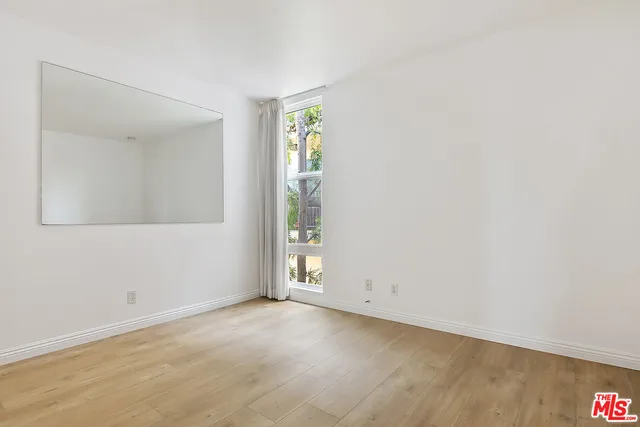 an empty room with wooden floor and mirror