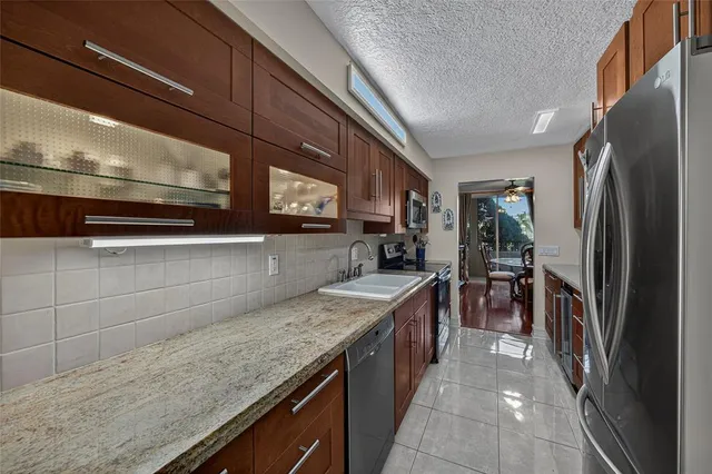 a kitchen with stainless steel appliances granite countertop a refrigerator a stove and a sink