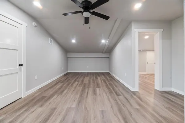 an empty room with wooden floor and windows