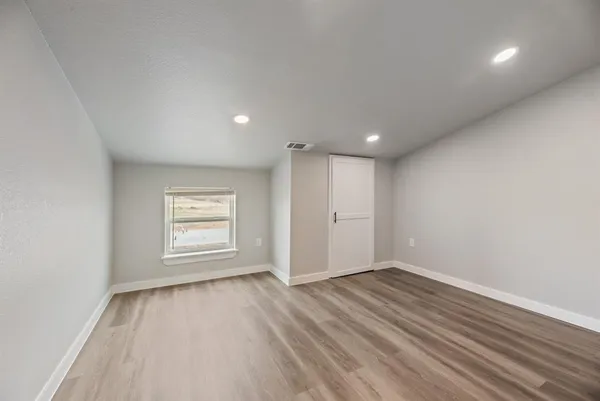 an empty room with wooden floor a ceiling fan and windows