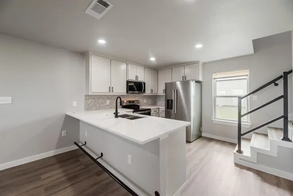 a kitchen with refrigerator cabinets and wooden floor