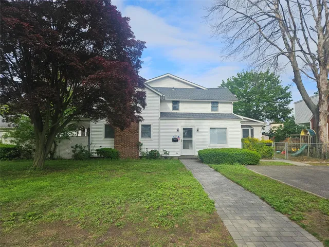 a front view of a house with a garden and trees