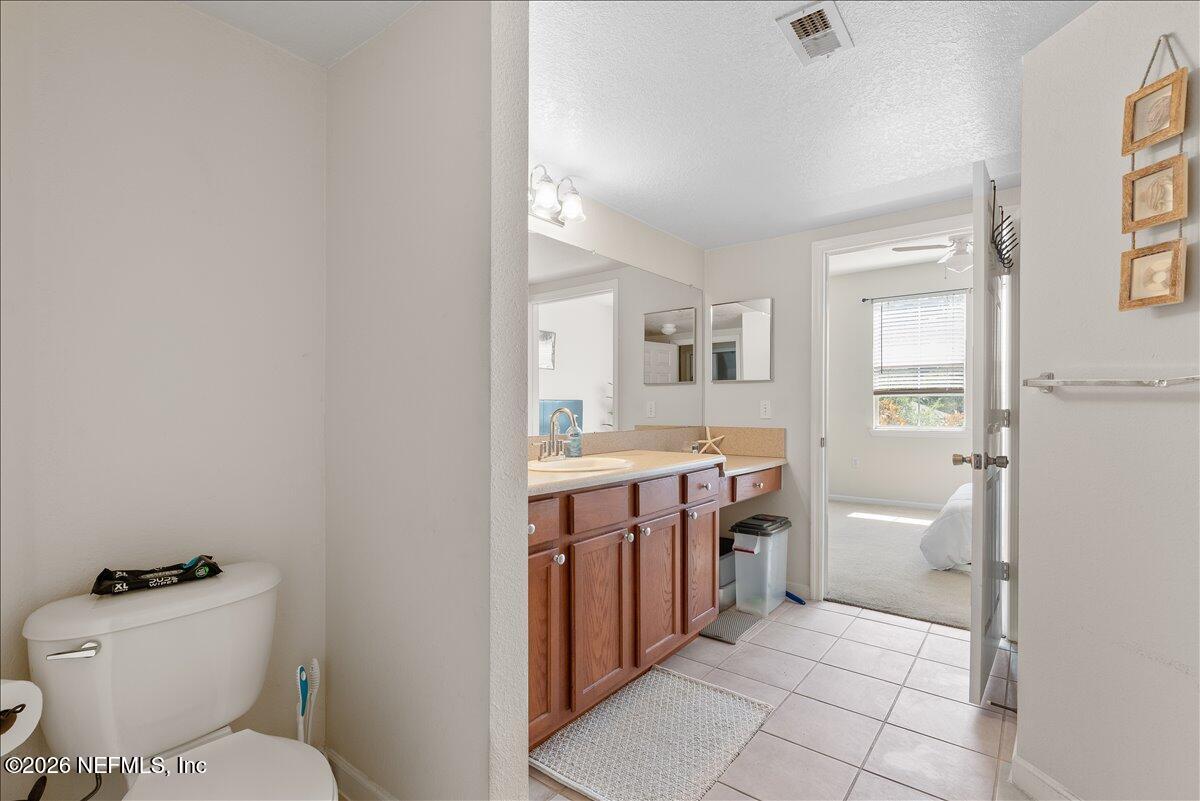8550 Touchton Road, Unit 1437 Jacksonville, FL 32216 - Photo 27 of 36 a bathroom with a granite countertop toilet sink and mirror
