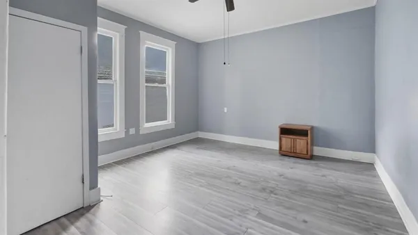 a view of an empty room with wooden floor and a window