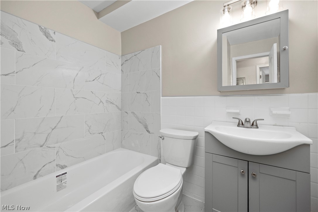5382 Lee Road, Unit 102 Maple Heights, OH 44137 - Photo 17 of 25 Bathroom featuring vanity, tile walls, a wainscoted wall, and bathing tub / shower combination