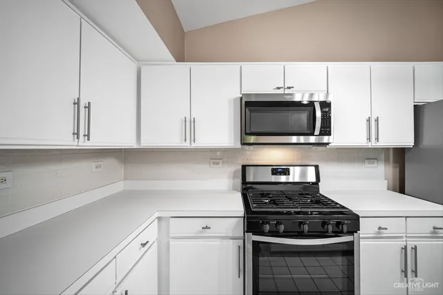 a kitchen with stainless steel appliances granite countertop white cabinets a stove top oven and granite counter tops