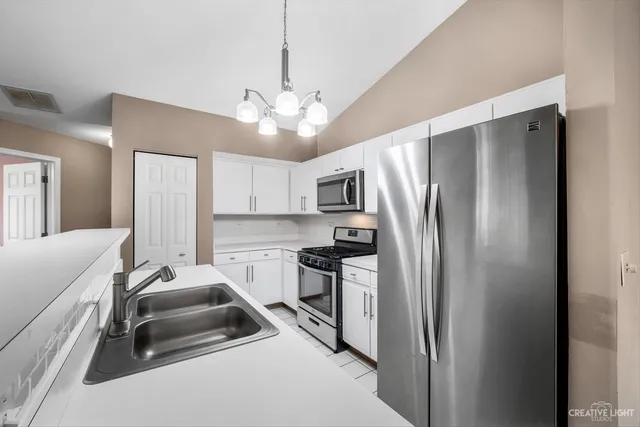 a kitchen with stainless steel appliances a refrigerator a sink dishwasher a stove and a refrigerator with wooden floor