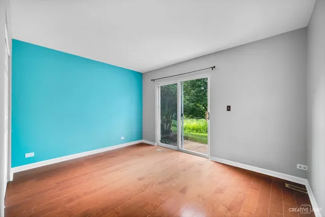 an empty room with floor to ceiling window and wooden floor