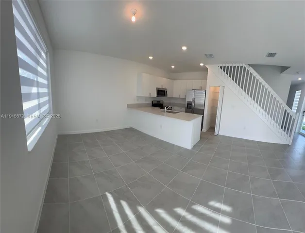 a living room with stainless steel appliances a couch and a window