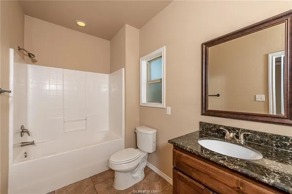 a bathroom with a granite countertop sink toilet a large mirror a bathtub and shower