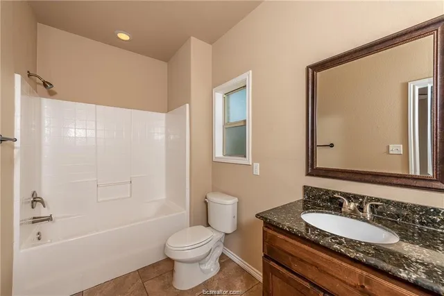 a bathroom with a granite countertop sink toilet a large mirror a bathtub and shower