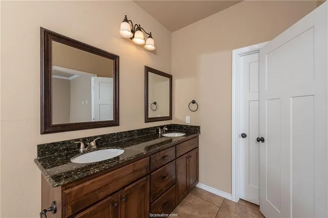 a bathroom with a granite countertop sink and a mirror