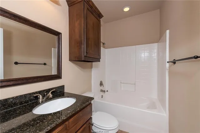 a bathroom with a granite countertop sink toilet and shower