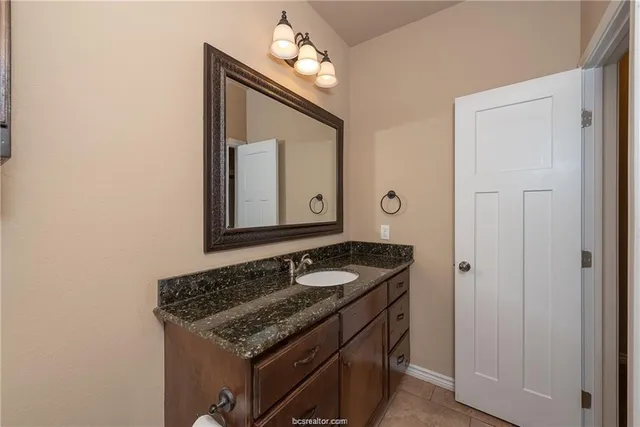 a bathroom with a granite countertop sink and a mirror