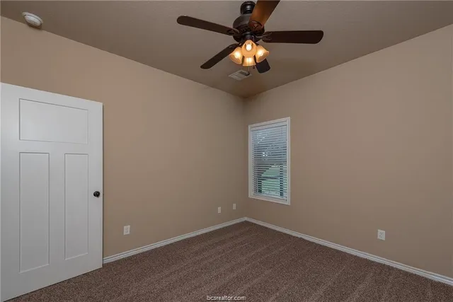 an empty room with a chandelier fan and windows