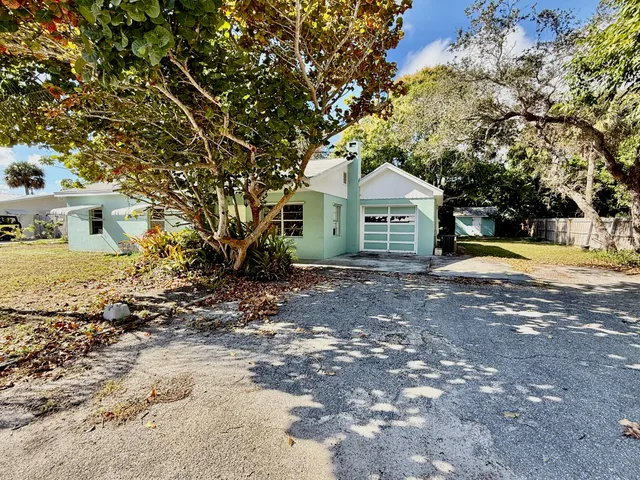 a view of a house with a yard and large tree