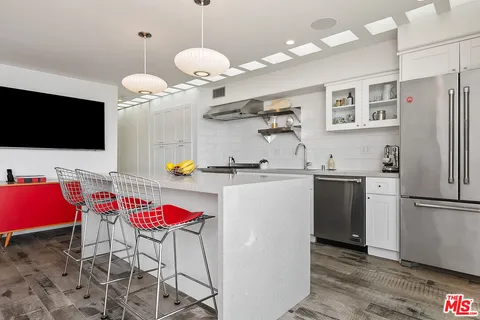 a kitchen with stainless steel appliances kitchen island granite countertop a refrigerator a stove a microwave oven a sink with island and chairs