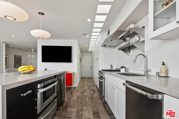 a view of kitchen with stainless steel appliances wooden floor dining table and chair