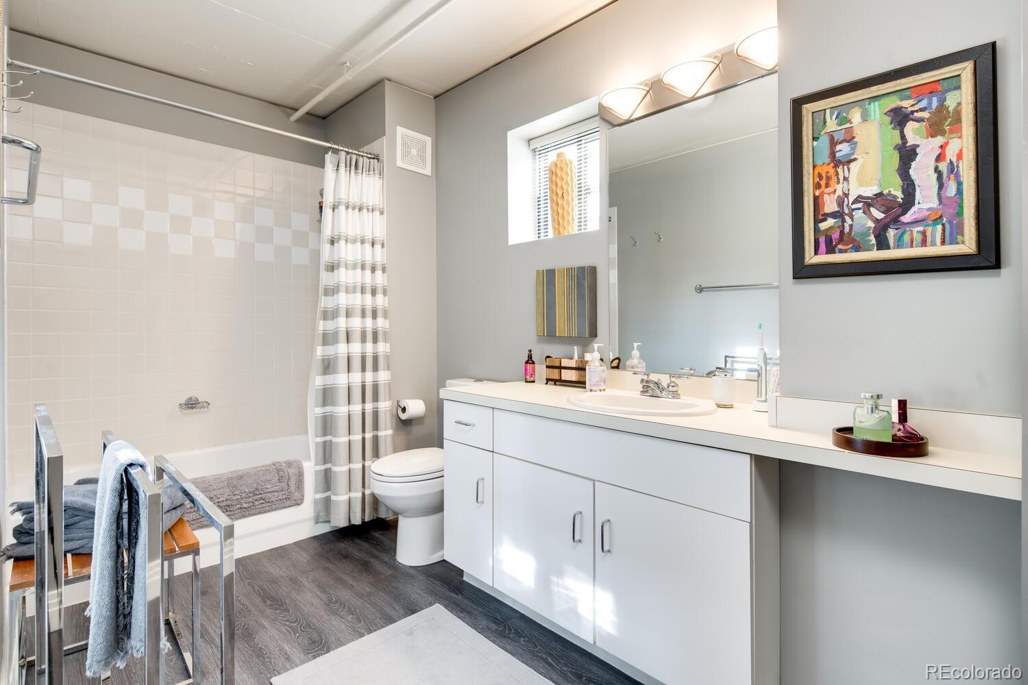 930 Acoma Street, Unit 212 Denver, CO 80204 - Photo 27 of 35 a bathroom with a double vanity sink a mirror a toilet and a shower