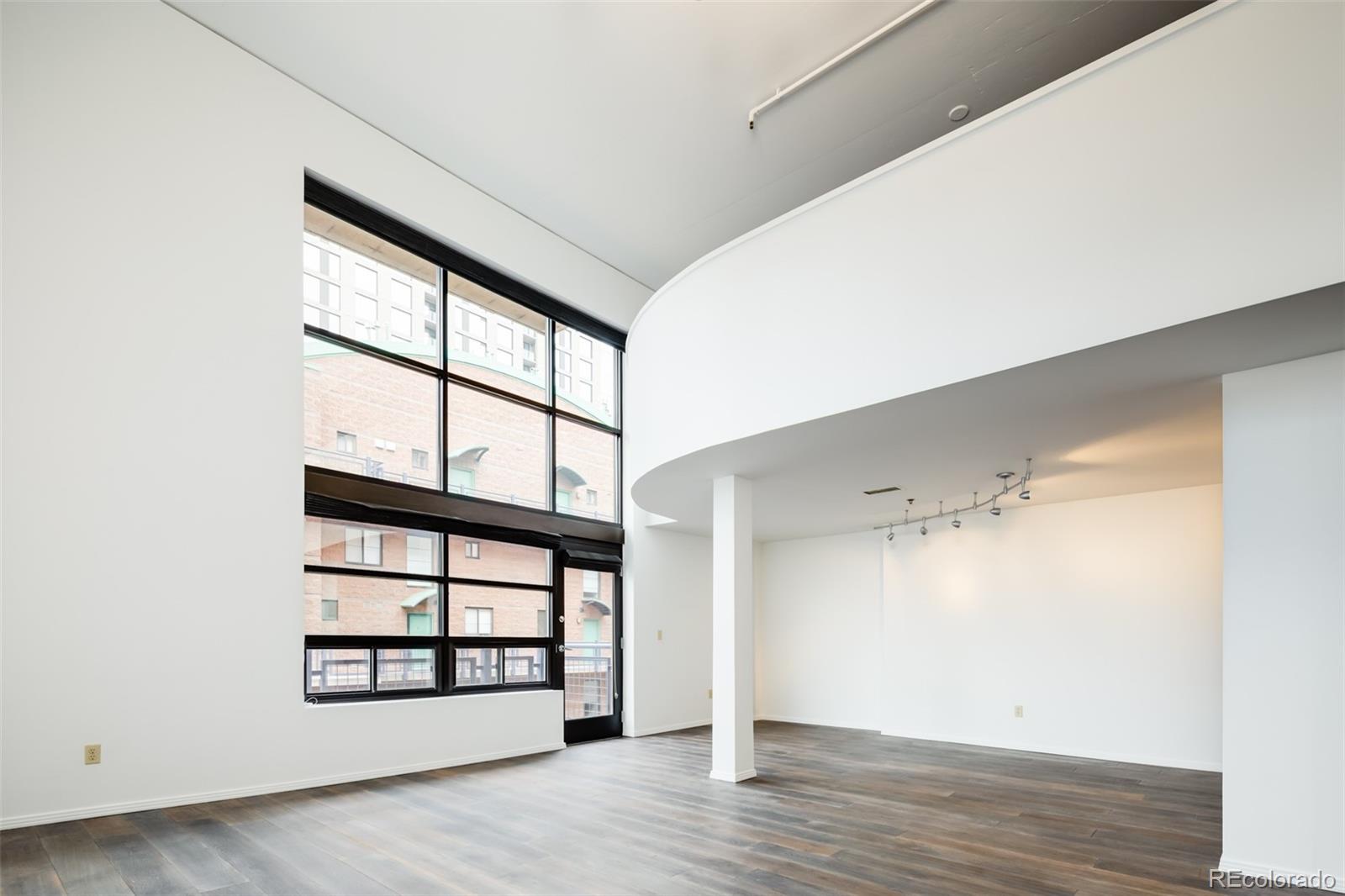 930 Acoma Street, Unit 212 Denver, CO 80204 - Photo 4 of 35 a view of an empty room with wooden floor and a window