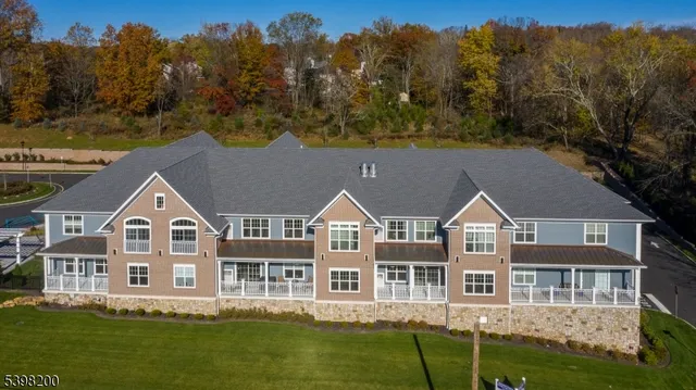 a aerial view of residential houses with yard and trees in the background