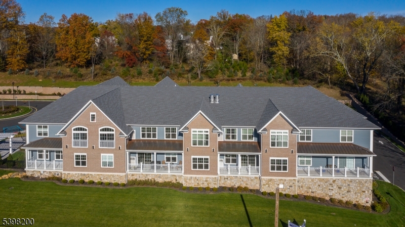 a aerial view of residential houses with yard and trees in the background