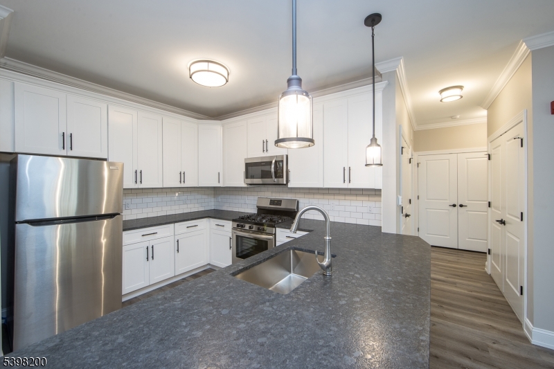 2435 Lamington Road, Unit 18 Bedminster, NJ 07921 - Photo 6 of 13 a kitchen with stainless steel appliances granite countertop a refrigerator a sink dishwasher a stove and white cabinets with wooden floor