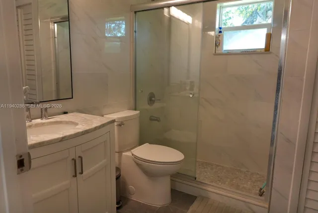 a bathroom with a granite countertop toilet a sink and a mirror