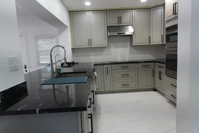 a kitchen with stainless steel appliances granite countertop a stove a sink and a microwave