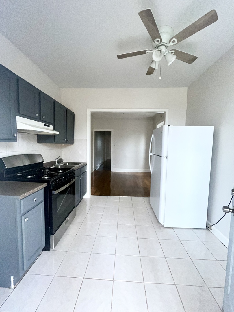 2140 North Kildare Avenue, Unit 2 Chicago, IL 60639 - Photo 10 of 11 a kitchen with a sink a stove top oven and cabinets