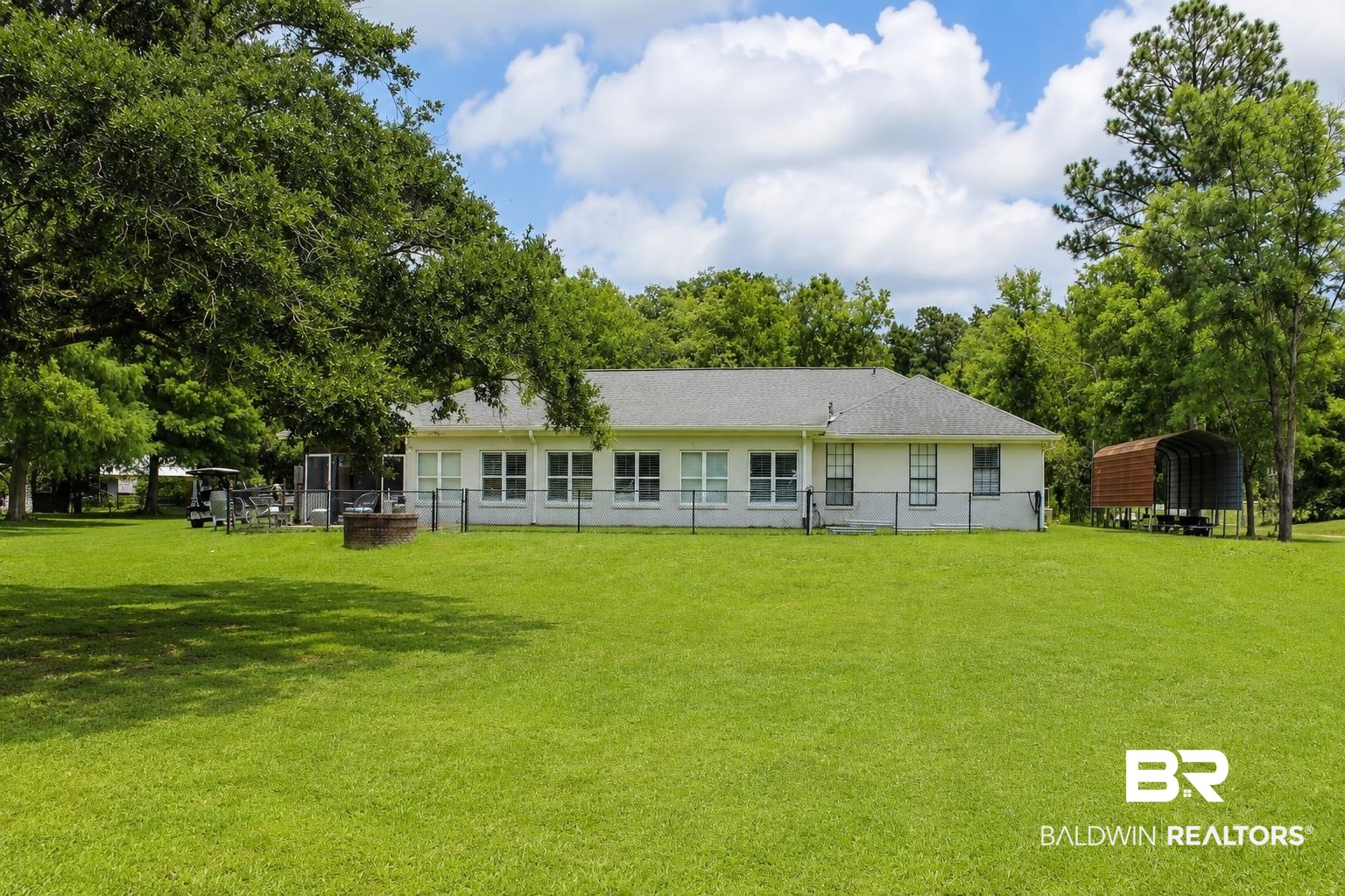 9825 Wolf Creek Ridge Elberta, AL 36530 - Photo 53 of 76 Spacious green lawn with mature trees and a single-story residence featuring multiple windows, a screened porch, and a dedicated outdoor fire pit