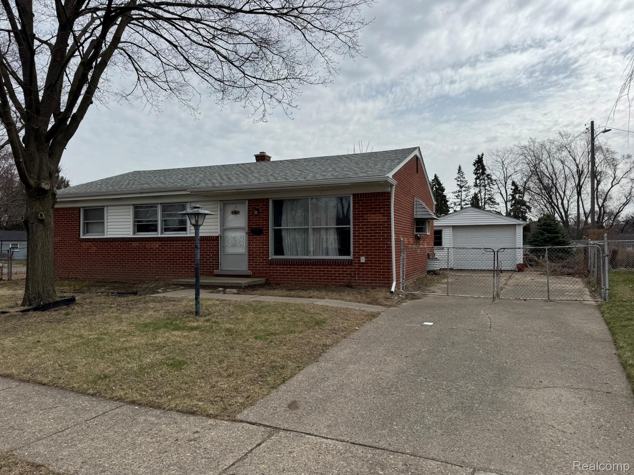 47166 Roland Street Utica, MI 48317 - Photo 3 of 18 View of front facade featuring an outbuilding, a garage, brick siding, a gate, and a chimney
