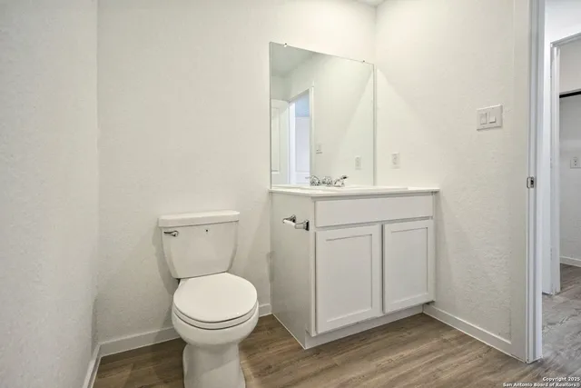 a bathroom with a toilet a sink and wooden floor