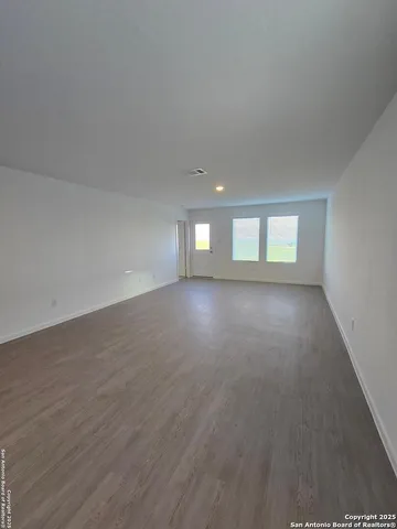a view of empty room with window and wooden floor