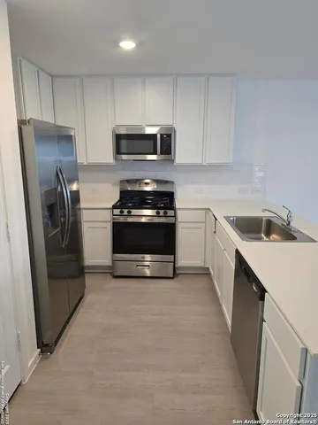 a kitchen with stainless steel appliances a stove a sink a refrigerator a microwave and cabinets