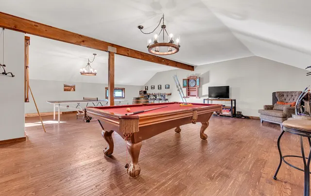 a room with wooden floor pool table and windows