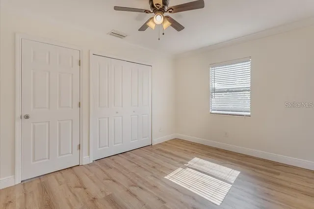 an empty room with wooden floor closet and windows