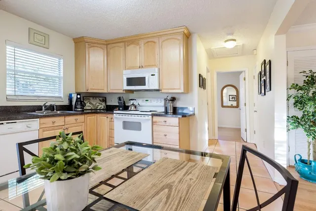 a kitchen with stainless steel appliances granite countertop a refrigerator a stove top oven a sink dishwasher and white cabinets with wooden floor
