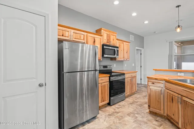 a kitchen with stainless steel appliances granite countertop a refrigerator a stove a sink and a microwave