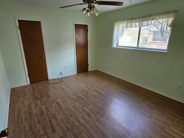 an empty room with a window and a chandelier fan