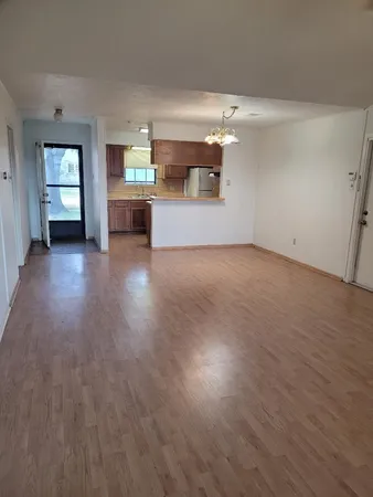 an empty room with wooden floor fireplace and windows