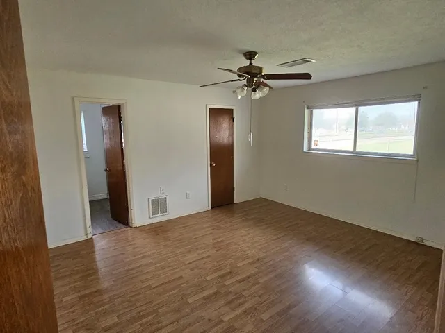 a view of empty room with wooden floor and fan
