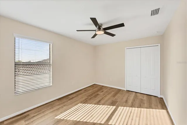an empty room with a window and a ceiling fan