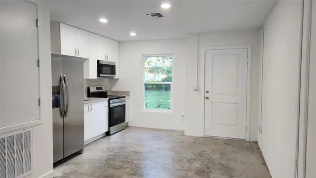 a kitchen with white cabinets and stainless steel appliances