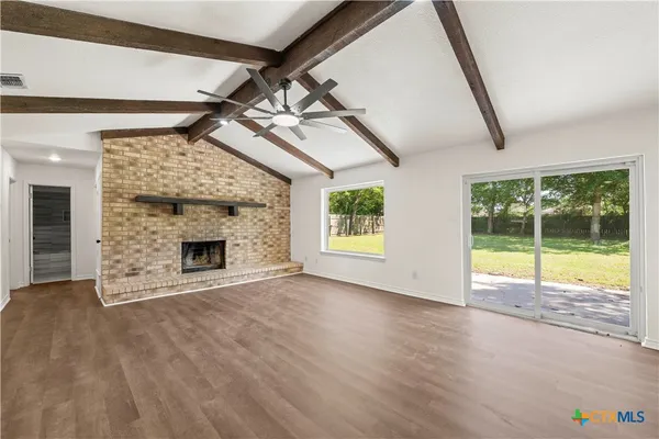 a view of an empty room with a fireplace and a window