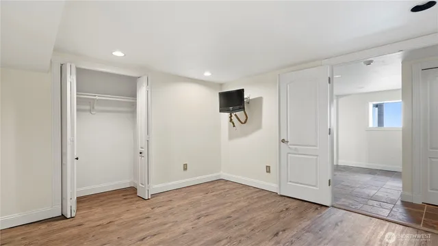 a view of an empty room with wooden floor & closet area
